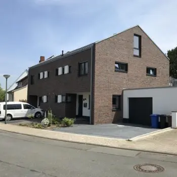 Ansicht eines modernen Doppelhauses mit Garage und PKW an der Straße