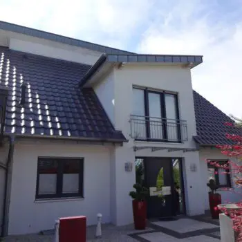 Ansicht eines modernen Einfamilienhauses (EFH) mit dunklem Ziegeldach und heller Fassade.