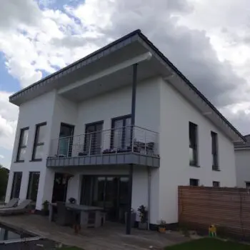 Modernes EFH mit Balkon, Terrasse und Pool unter bewölktem Himmel, attraktives Wohnhaus Design.