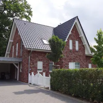EFH-2: Ansicht eines zweistöckigen Einfamilienhauses mit roten Backsteinen und dunklem Ziegeldach.