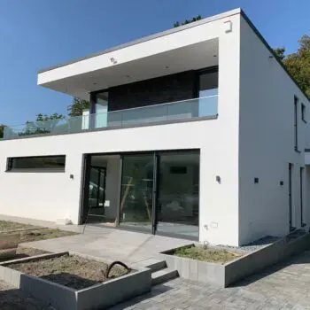 Modernes zweistöckiges EFH-Haus mit Flachdach, Balkon und großen Schiebefenstern in strahlendem Weiß.