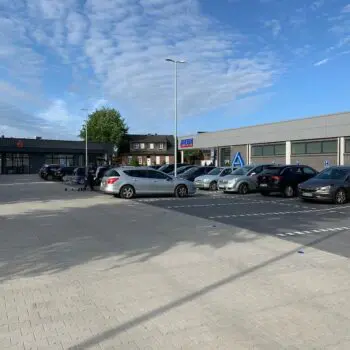 Parkplatz vor einem Aldi-Markt mit geparkten Autos und blauem Himmel. Gewerbe.