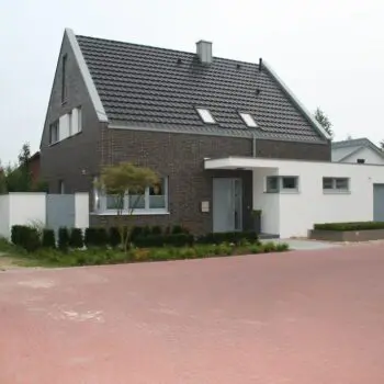 IMG_9614: Modernes Einfamilienhaus mit dunklem Ziegeldach und Garage, umgeben von gepflasterter Fläche