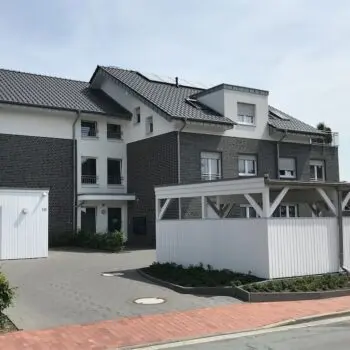 Mehrfamilienhaus (MFH-27): Modernes Gebäude mit dunklen Ziegeln und hellen Fassadenelementen, graues Ziegeldach.