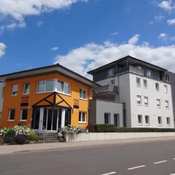 Ansicht einer Soziale Einrichtung mit einem orangefarbenen und einem weißen Gebäude bei Tageslicht.