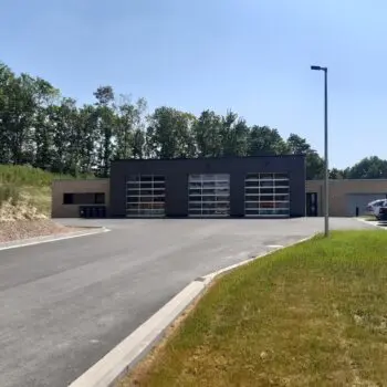 Ansicht eines Feuerwehr-Gebäudes mit großen Toren und Parkplätzen.
