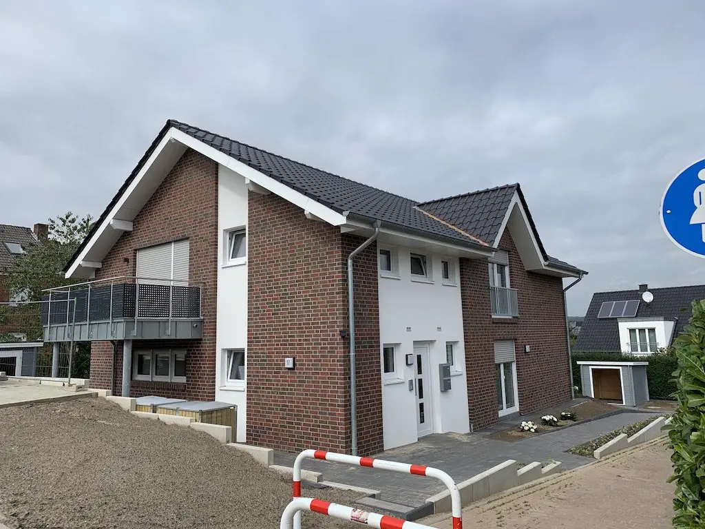 Ansicht eines modernen zweigeschossigen Einfamilienhauses mit Ziegelmauerwerk und einem kleinen Balkon.
