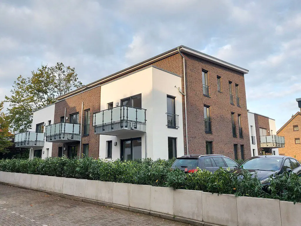 Aussenansicht eines modernen Mehrfamilienhauses mit Backsteinfassade und Balkonen unter bewölktem Himmel.