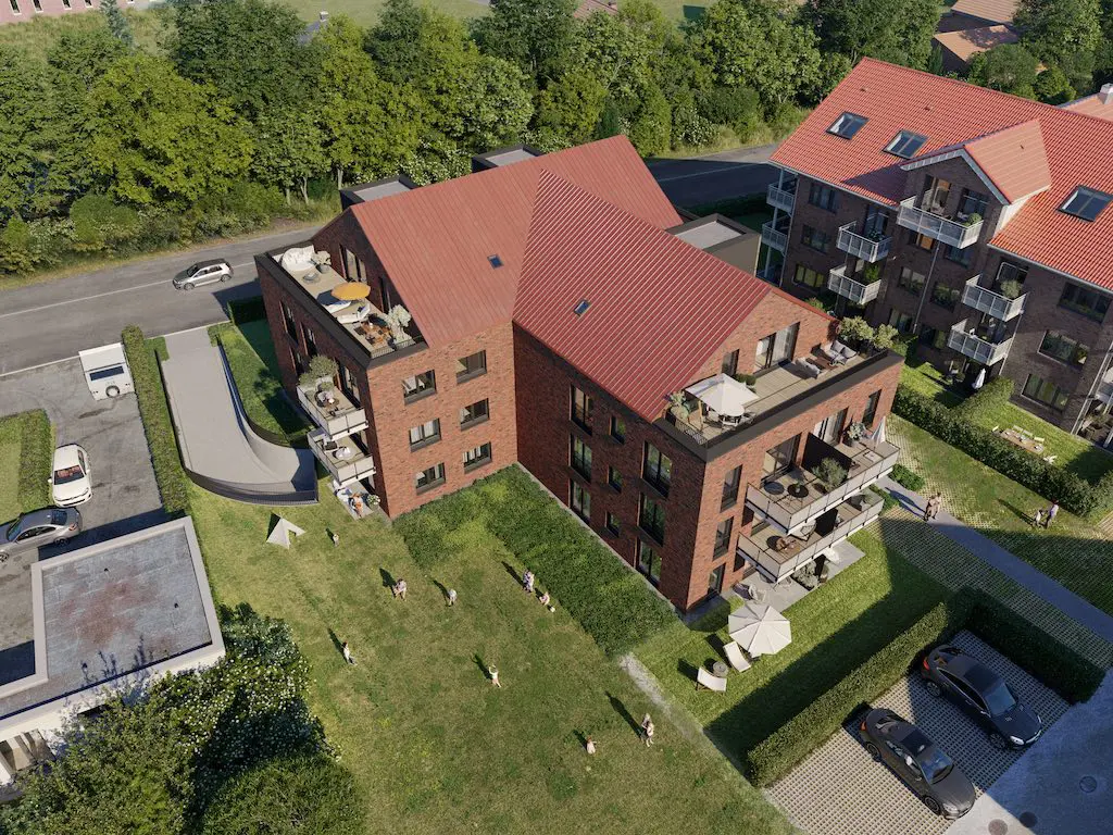 Ansicht eines Mehrfamilienhauses mit roten Ziegeln und begrünten Außenbereichen, aufgenommen aus der Vogelperspektive.