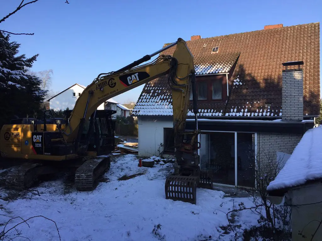 Abbruch eines Altbaus: Bagger bei Abbrucharbeiten an einem Wohnhaus im Winter.