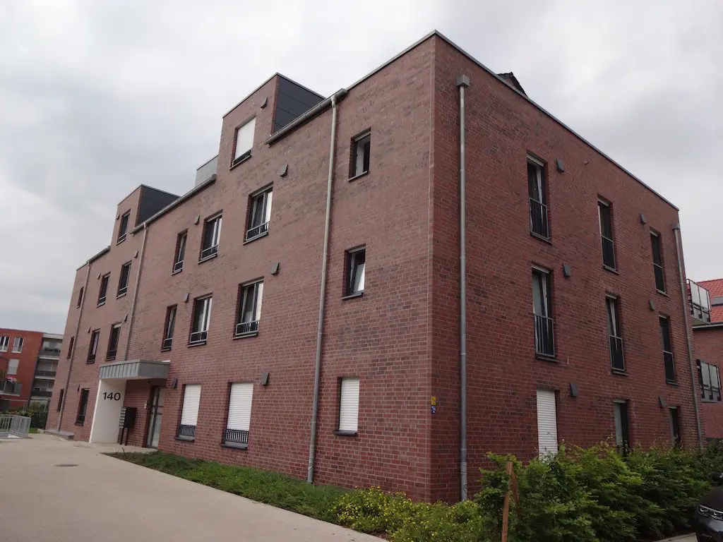 Mehrgeschossiges Backsteingebäude mit dunklen Fensterrahmen unter bewölktem Himmel, Salzmannstraße 140.