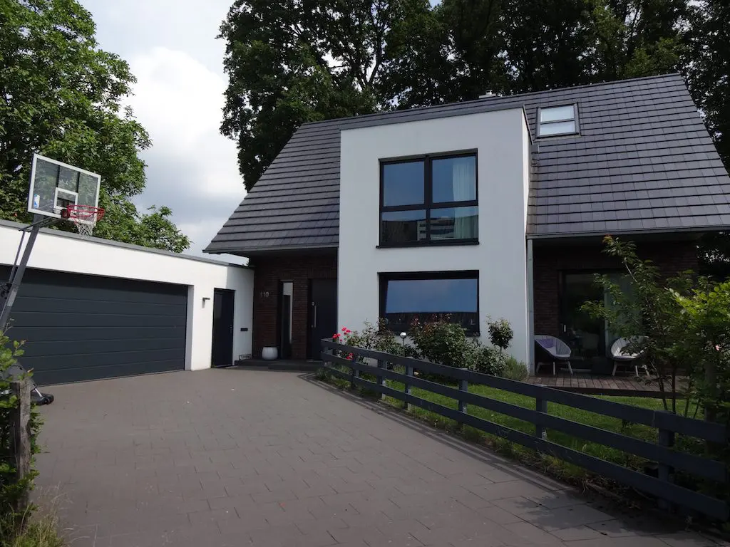Fotografie eines modernen Einfamilienhauses (EFH-1) mit Garage, einem Basketballkorb und gepflasterter Einfahrt.