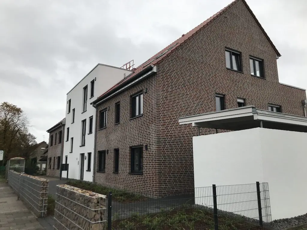 IMG_8118.jpg: Mehrfamilienhäuser mit Fassaden aus Backstein und Putz unter bewölktem Himmel.