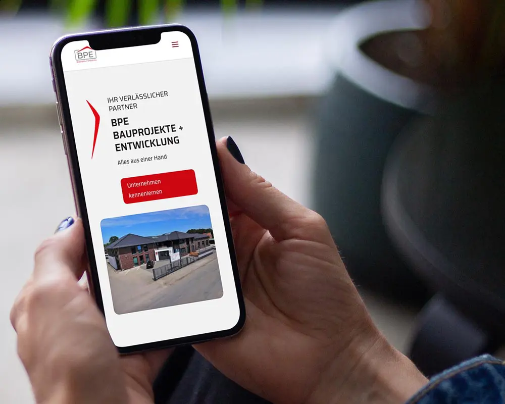 Mobile-Mockup: Frau hält Smartphone mit neuer Webseite für Bauprojekte und Entwicklung in der Hand.