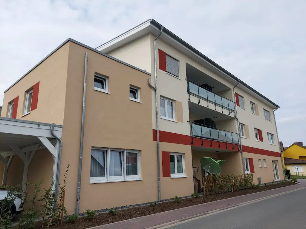 Wohnanlage mit Tagespflege: Mehrgeschossiges Gebäude mit Balkonen und farbigen Akzenten, Ansicht von aussen.