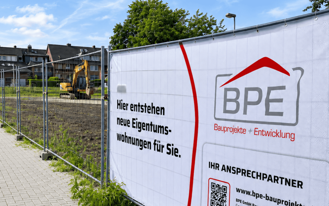 Großes Werbebanner einer Immobilienfirma an einem Bauzaun vor einer vorbereiteten Fläche für Eigentumswohnungen