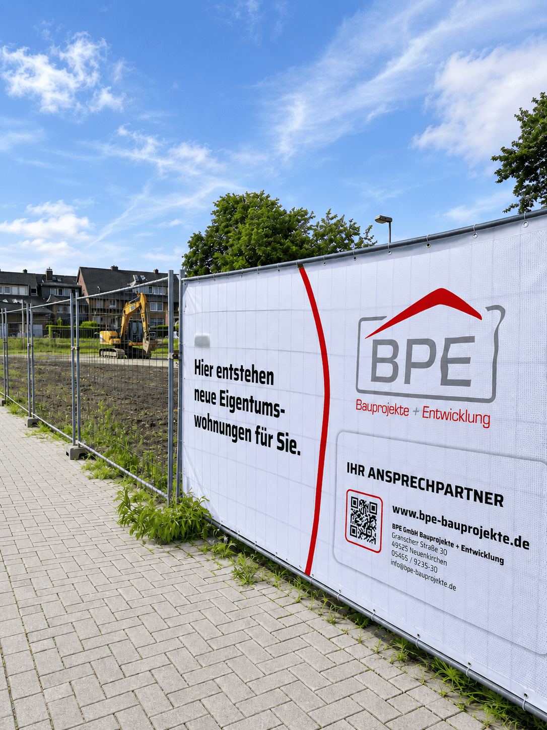 Großes Werbebanner einer Immobilienfirma an einem Bauzaun vor einer vorbereiteten Fläche für Eigentumswohnungen