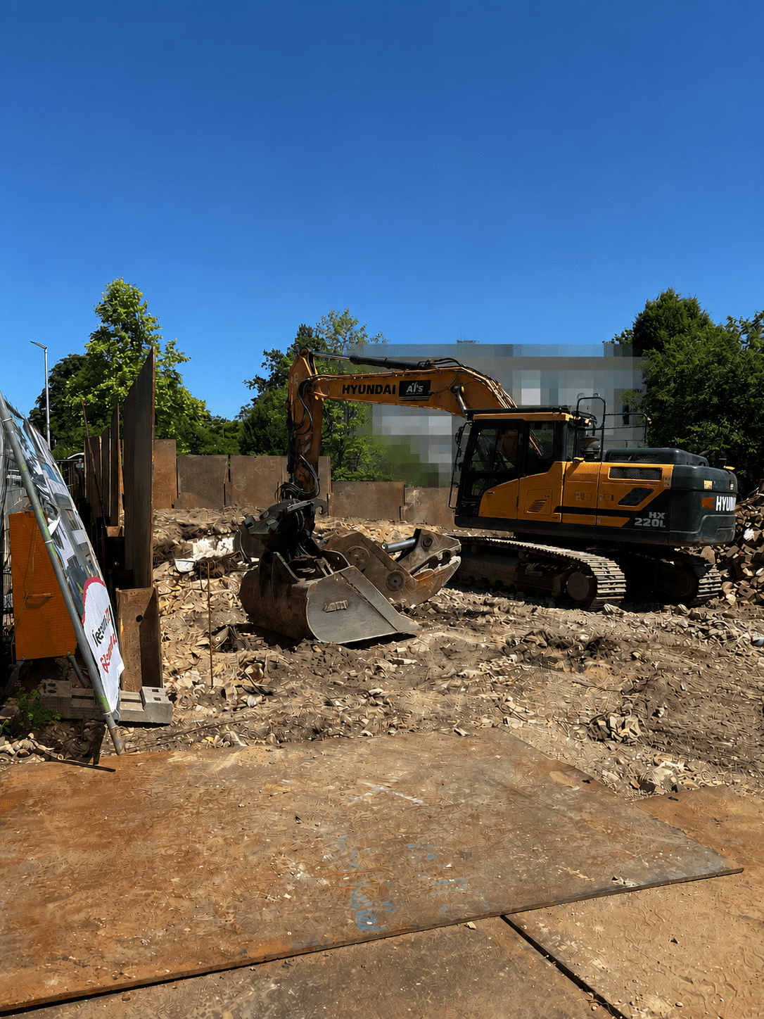 Gelber Kettenbagger bei Erdarbeiten auf einer sonnigen Baustelle mit Metallwänden und freiem Boden